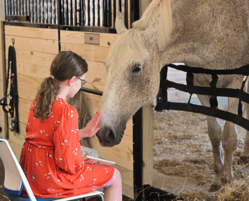 Reading Wrangler participant reaches out to pet her horse Will while reading him a story